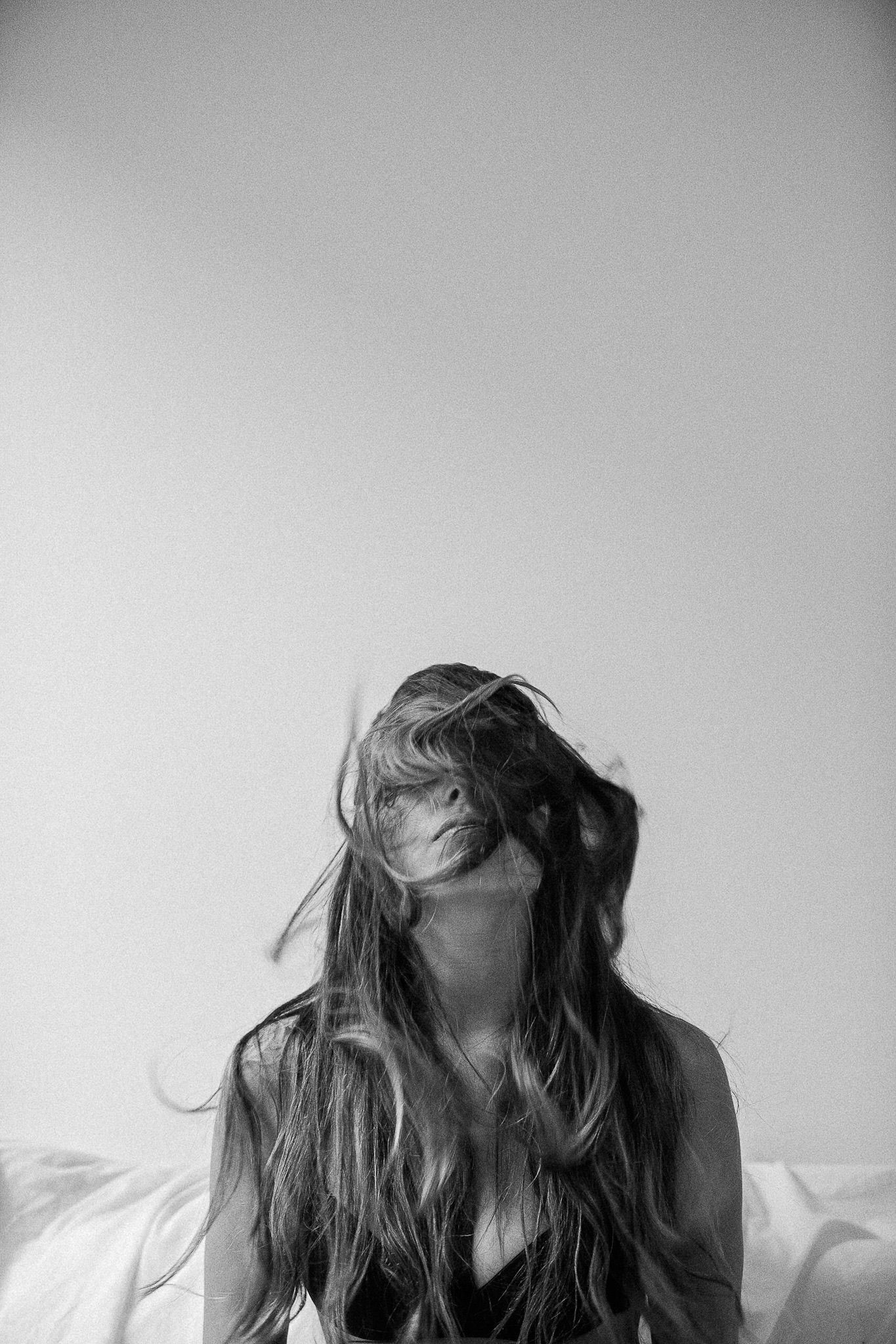 Black and white artistic portrait series showing dynamic hair movement against light background.