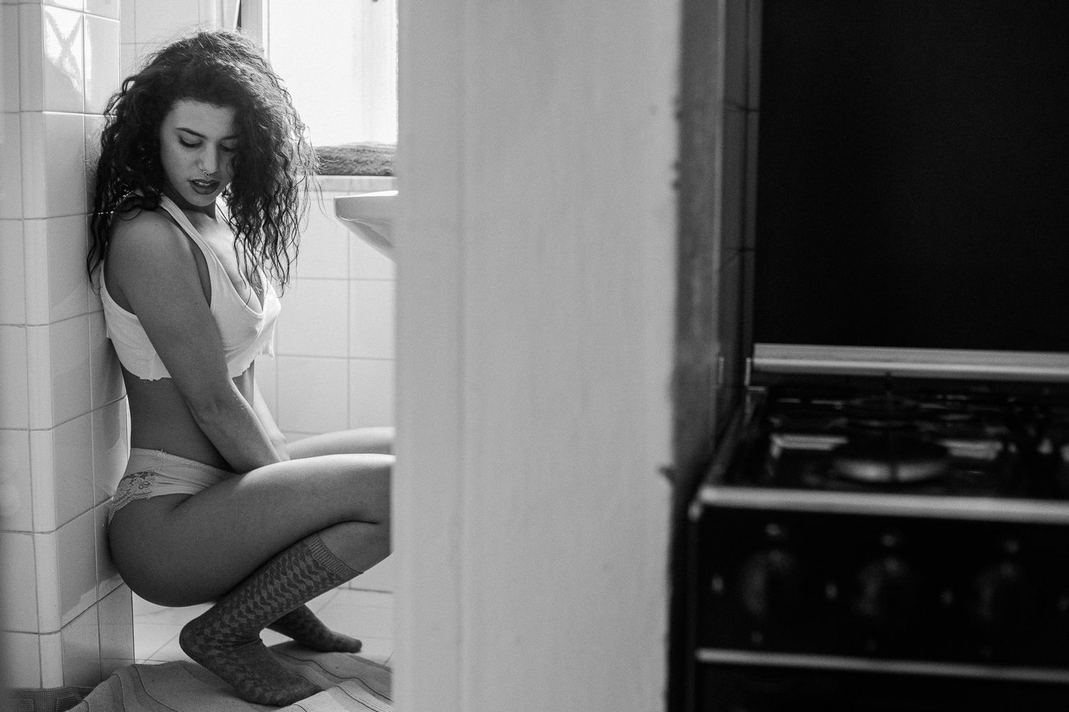 Black and white photo series showing a person in various poses by a window, creating a moody artistic composition.