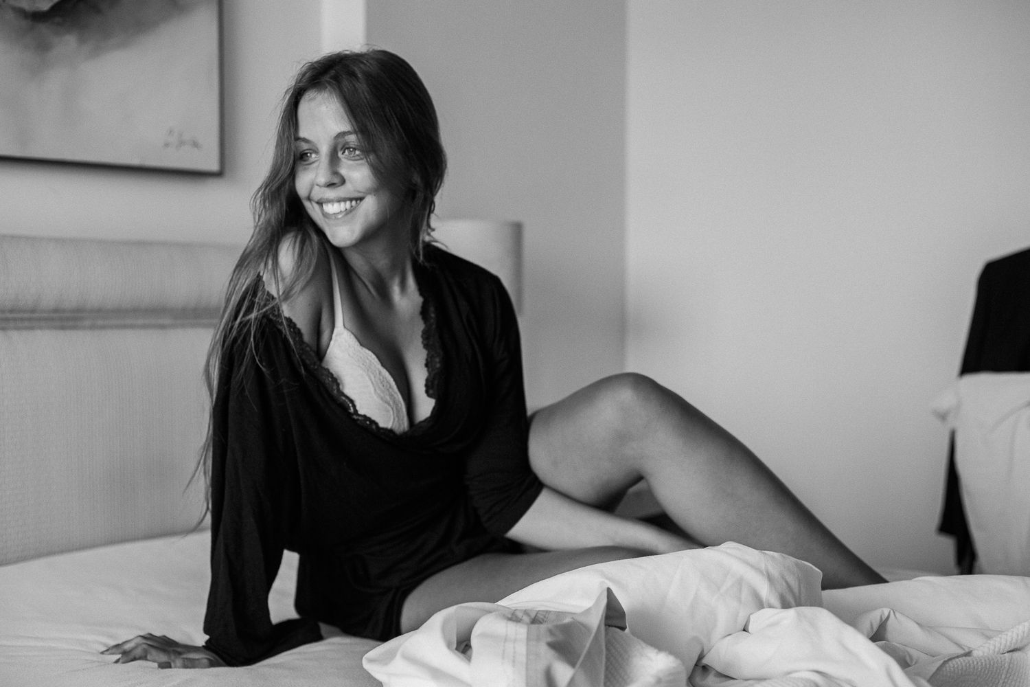 A black and white photo series shows intimate moments of someone smiling and relaxing on a bed.