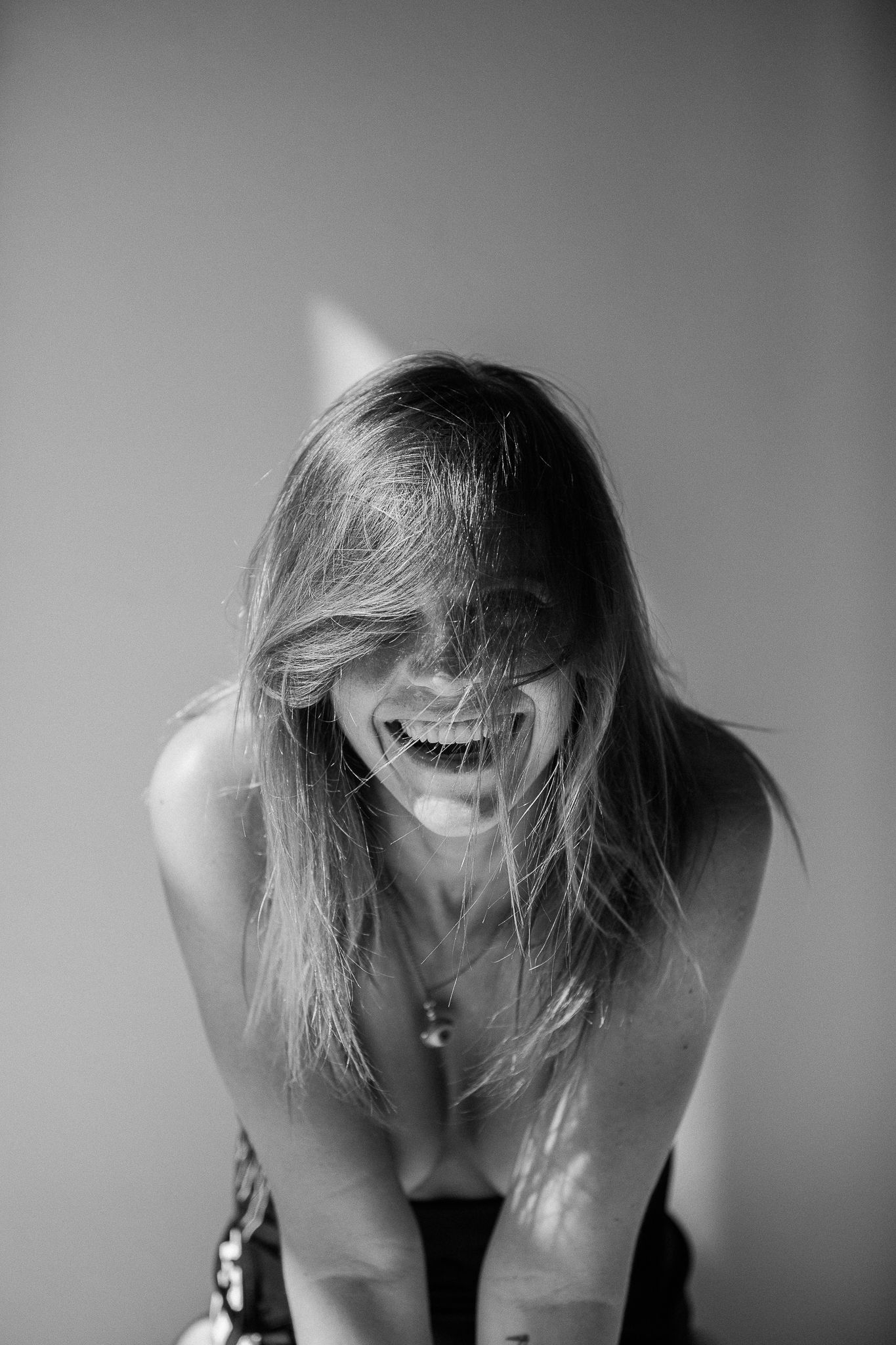 Black and white artistic photo series showing a person with windswept hair bending forward in dramatic poses.