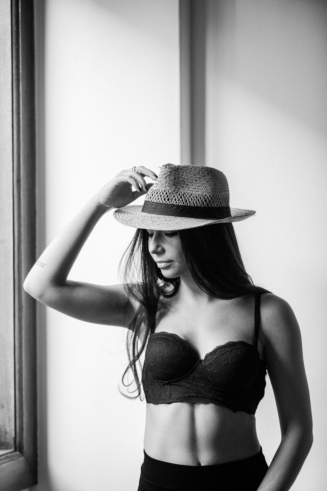 Minimalist boudoir photography series featuring a woman in black lingerie and a hat against a white background.