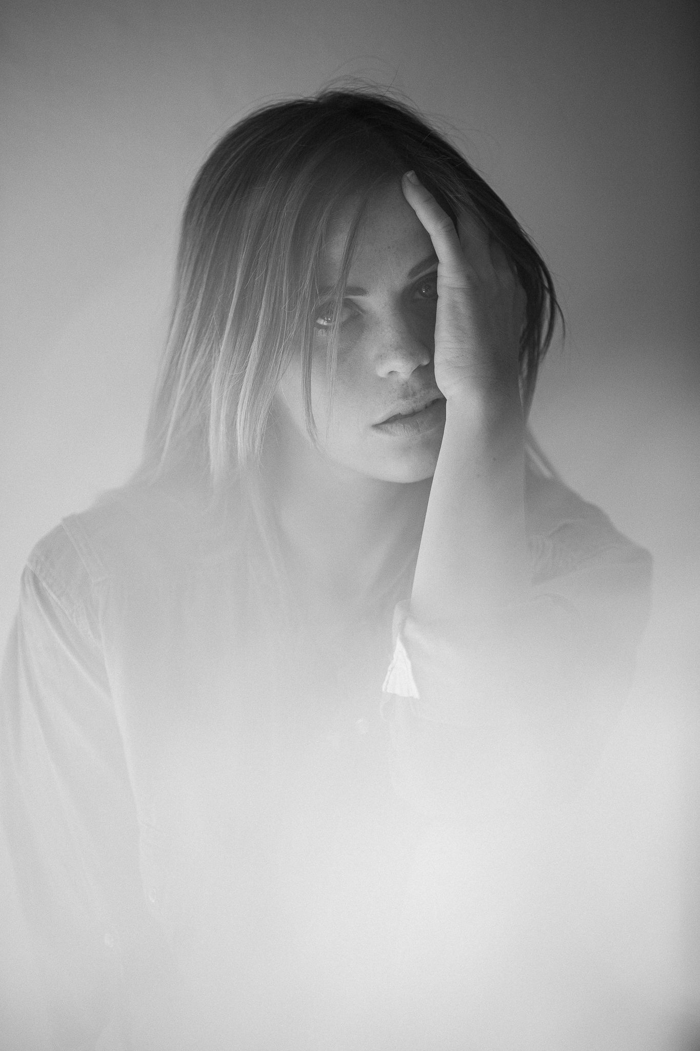 A series of moody black and white portraits showing a silhouetted figure with hair movement against a light background.