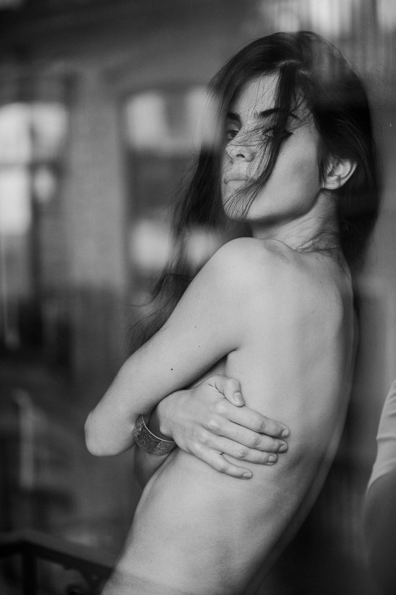 Artistic black and white boudoir photo with dramatic shadows and window light.