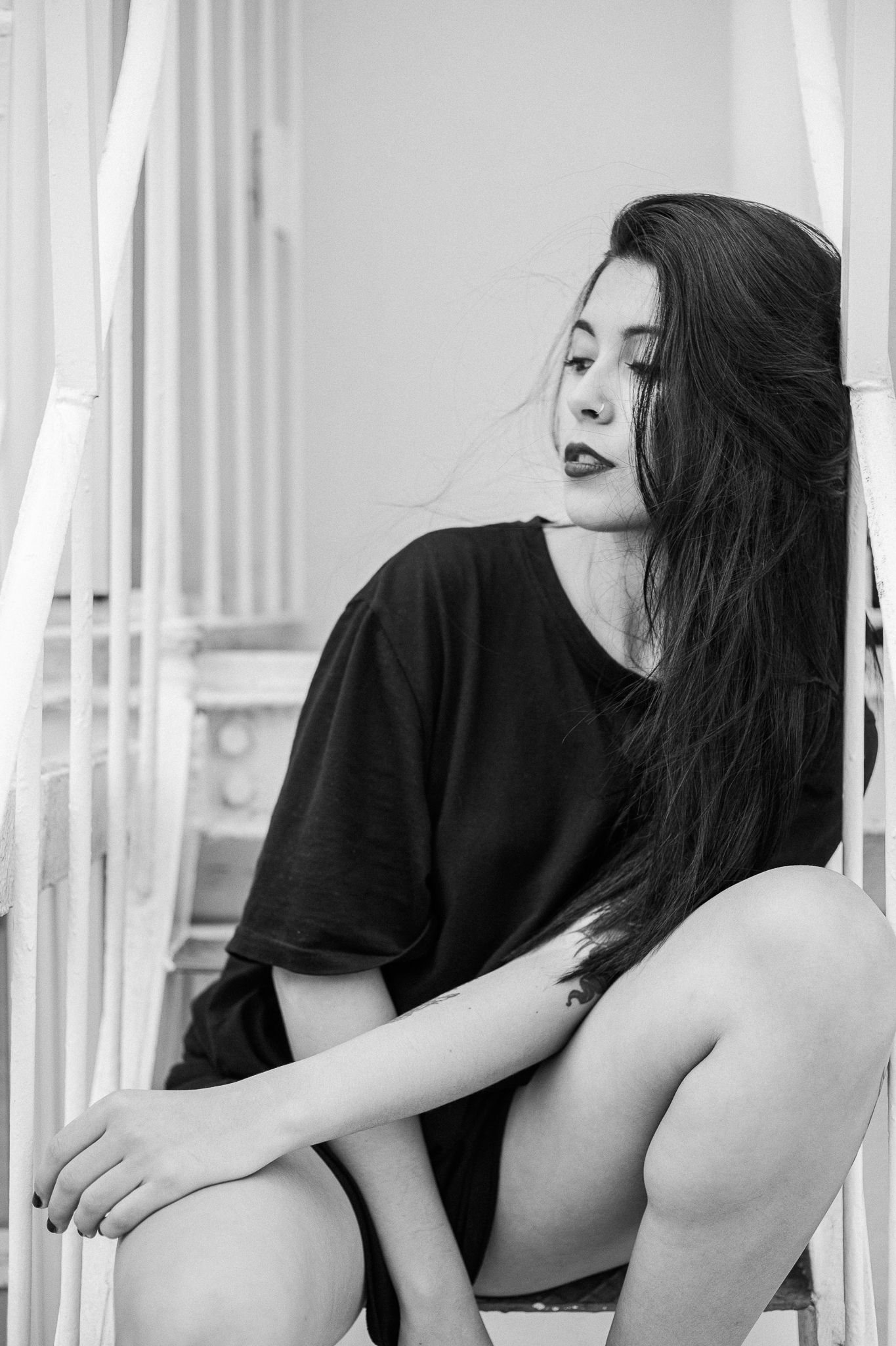 Black and white artistic portrait series showing a person in dark clothing leaning against white vertical bars.