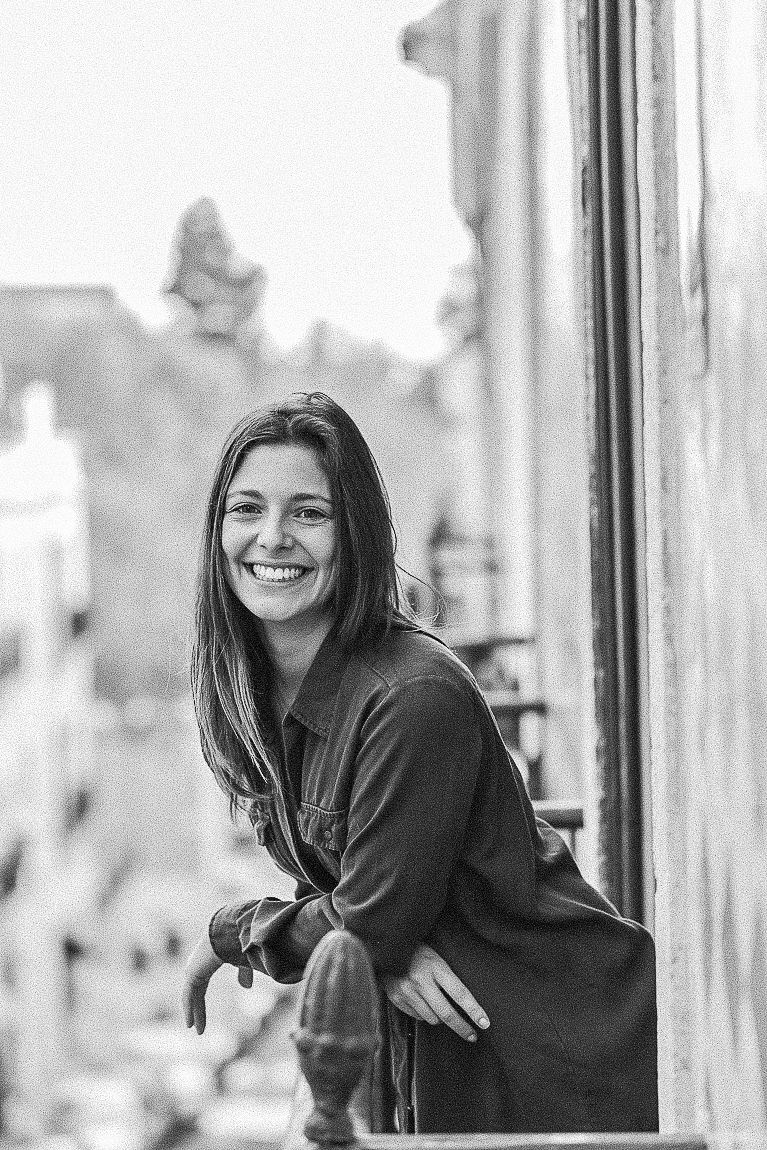 A black and white photo series showing someone in a dark sweater leaning and smiling by a window.