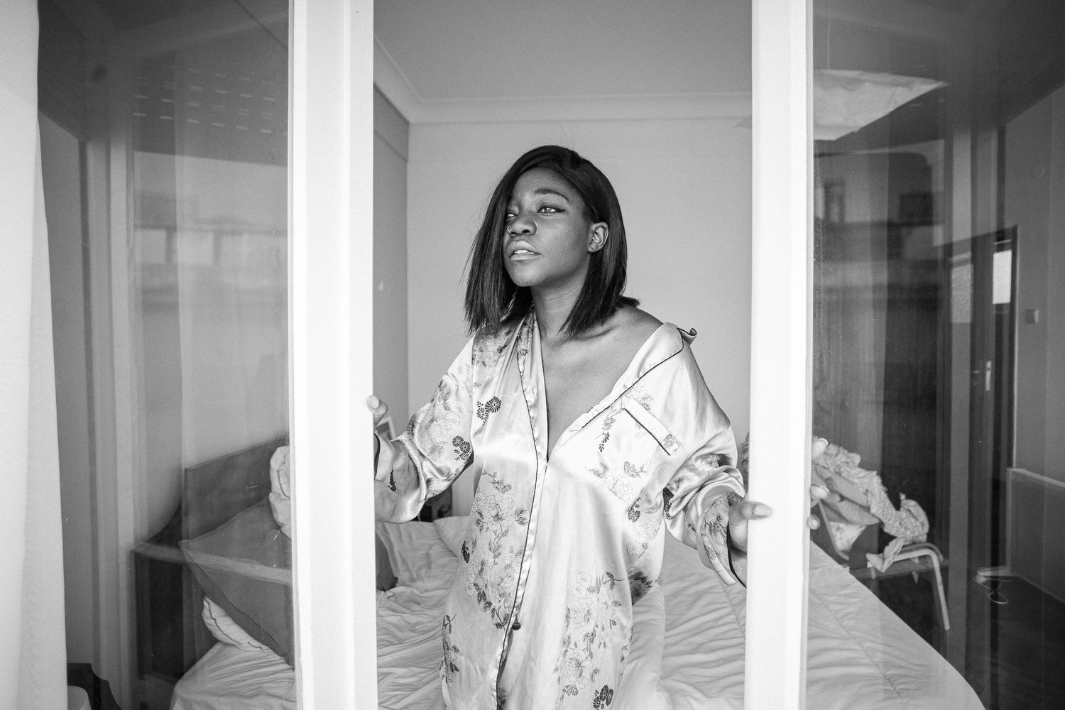 A black and white photo series showing someone posing in different positions against white walls and columns.