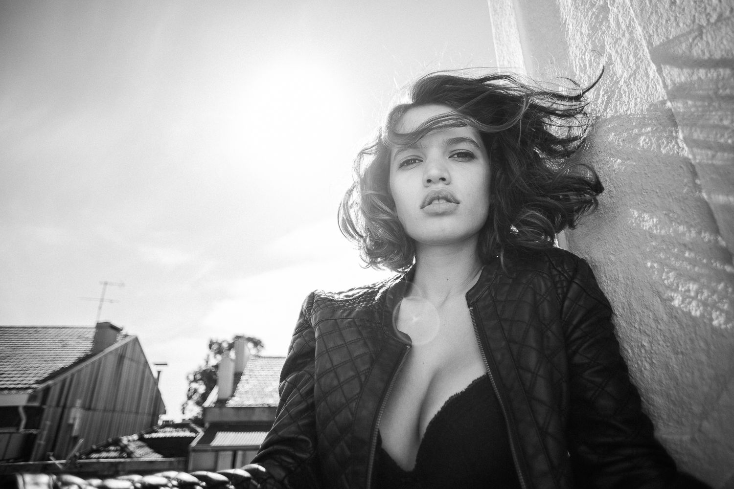 A series of black and white artistic portrait photographs showing dramatic lighting and poses against textured walls.
