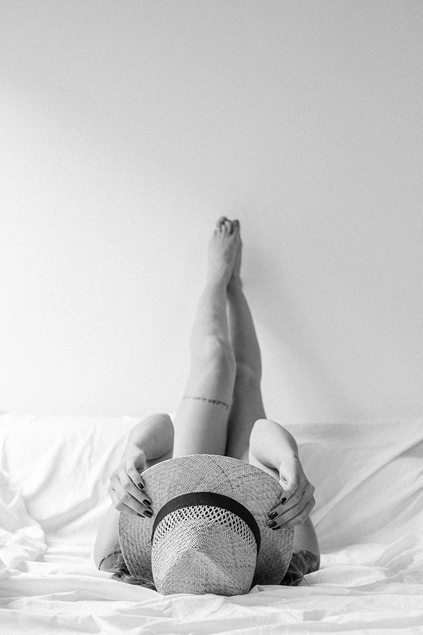 Artistic black and white photo of person reclining on white sheets.