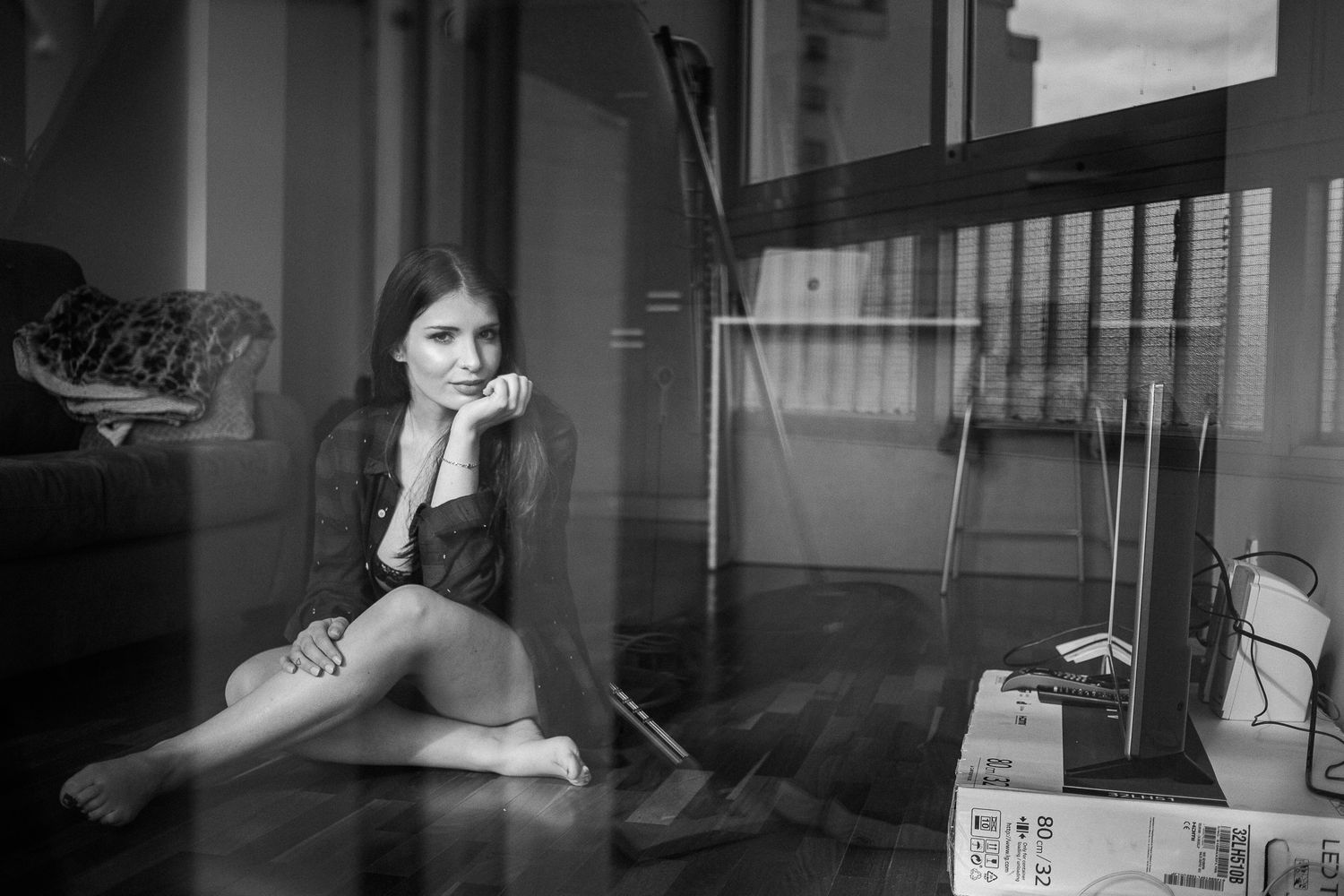 Moody black and white indoor portrait with reflective glass elements.