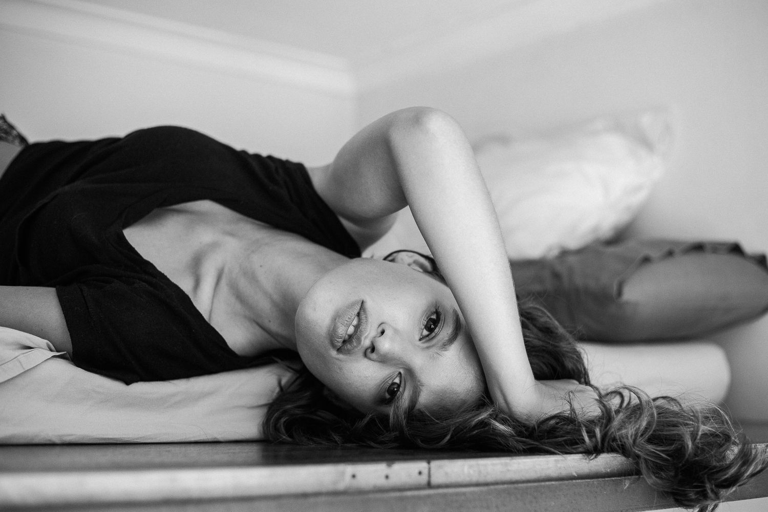 A series of black and white artistic boudoir photos showing intimate poses on a bed and floor.