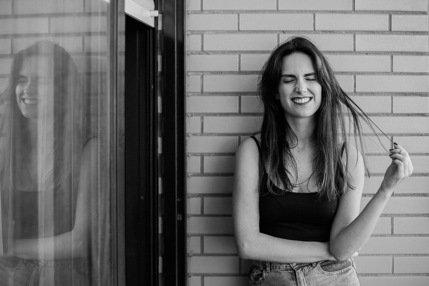 Woman in a black dress poses playfully against a white brick wall in a series of candid shots.