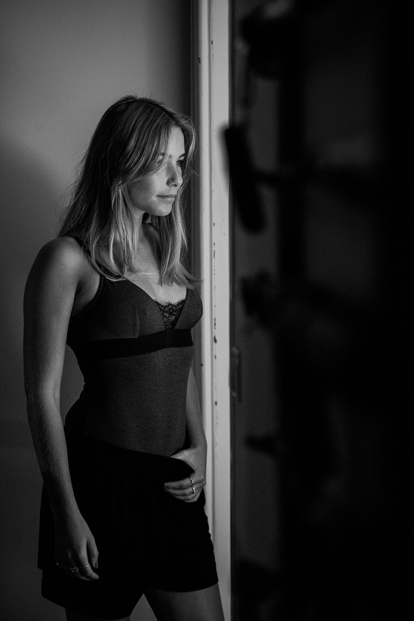 A series of black and white photographs showing a figure in dark clothing standing near a window in dramatic lighting.