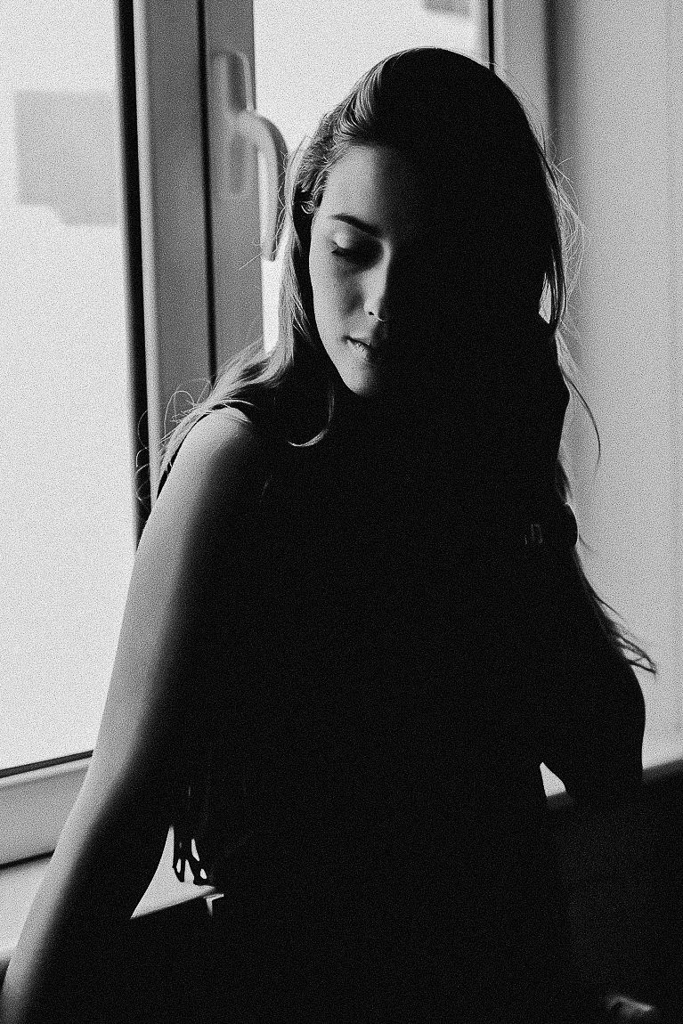 Silhouetted profile of a person with long dark hair in a black and white artistic portrait series.