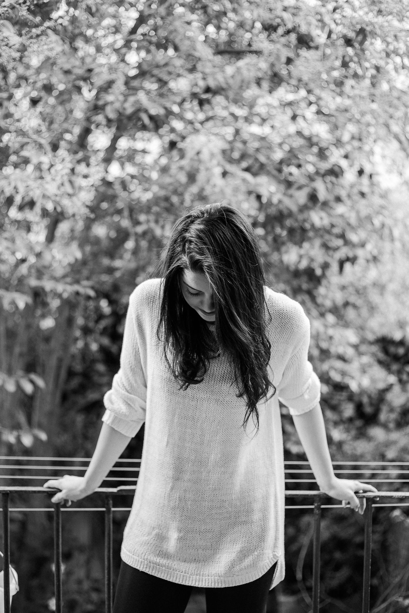 Black and white photo series showing a person in white top leaning over a railing with trees in background.