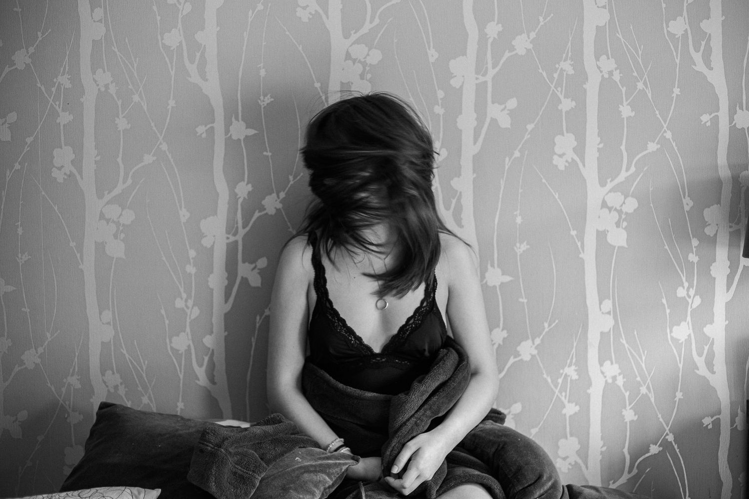 Artistic black and white portrait series with delicate floral wallpaper patterns in the background.