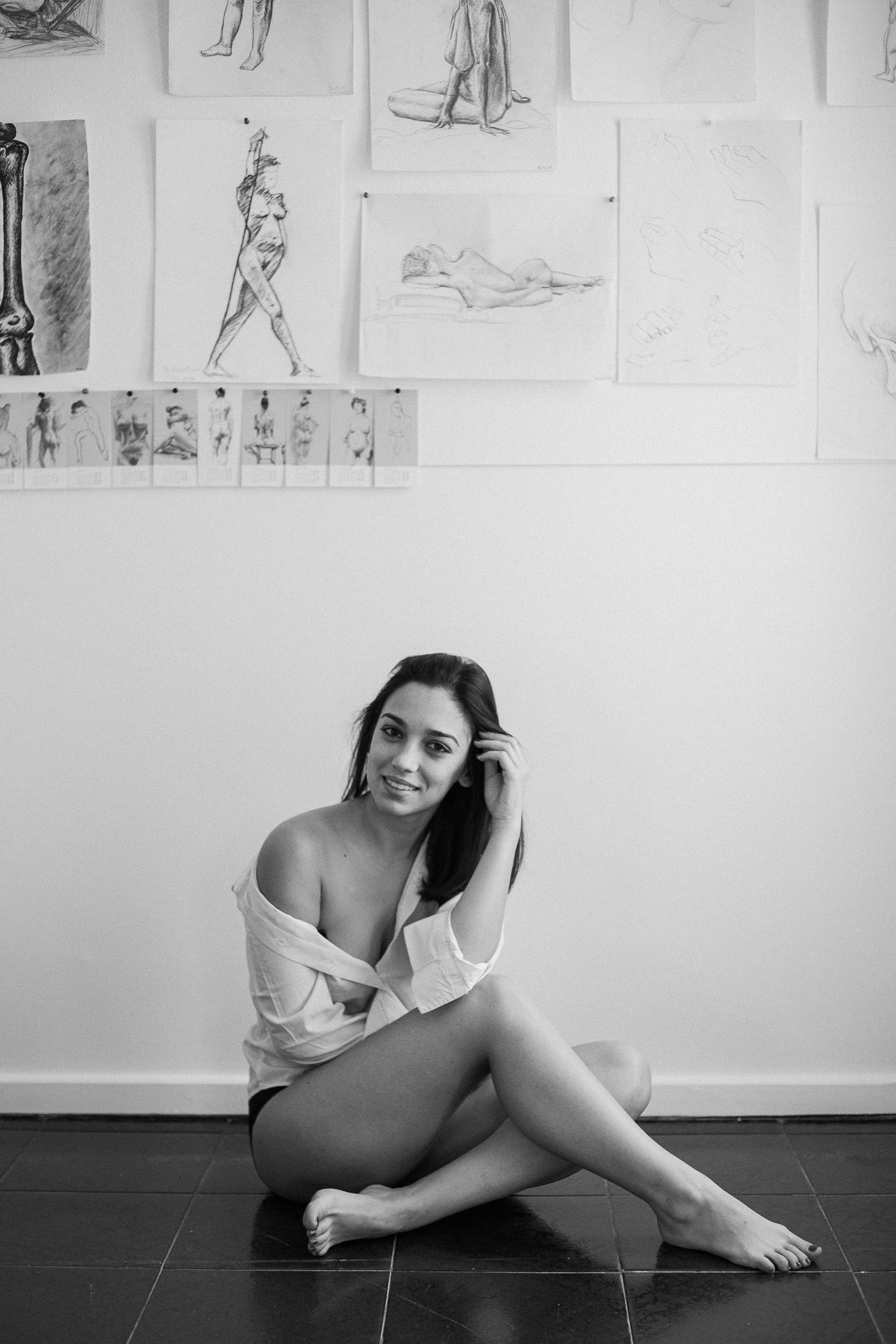 Black and white artistic photo series showing a figure in various reclining poses against a wall with sketches.