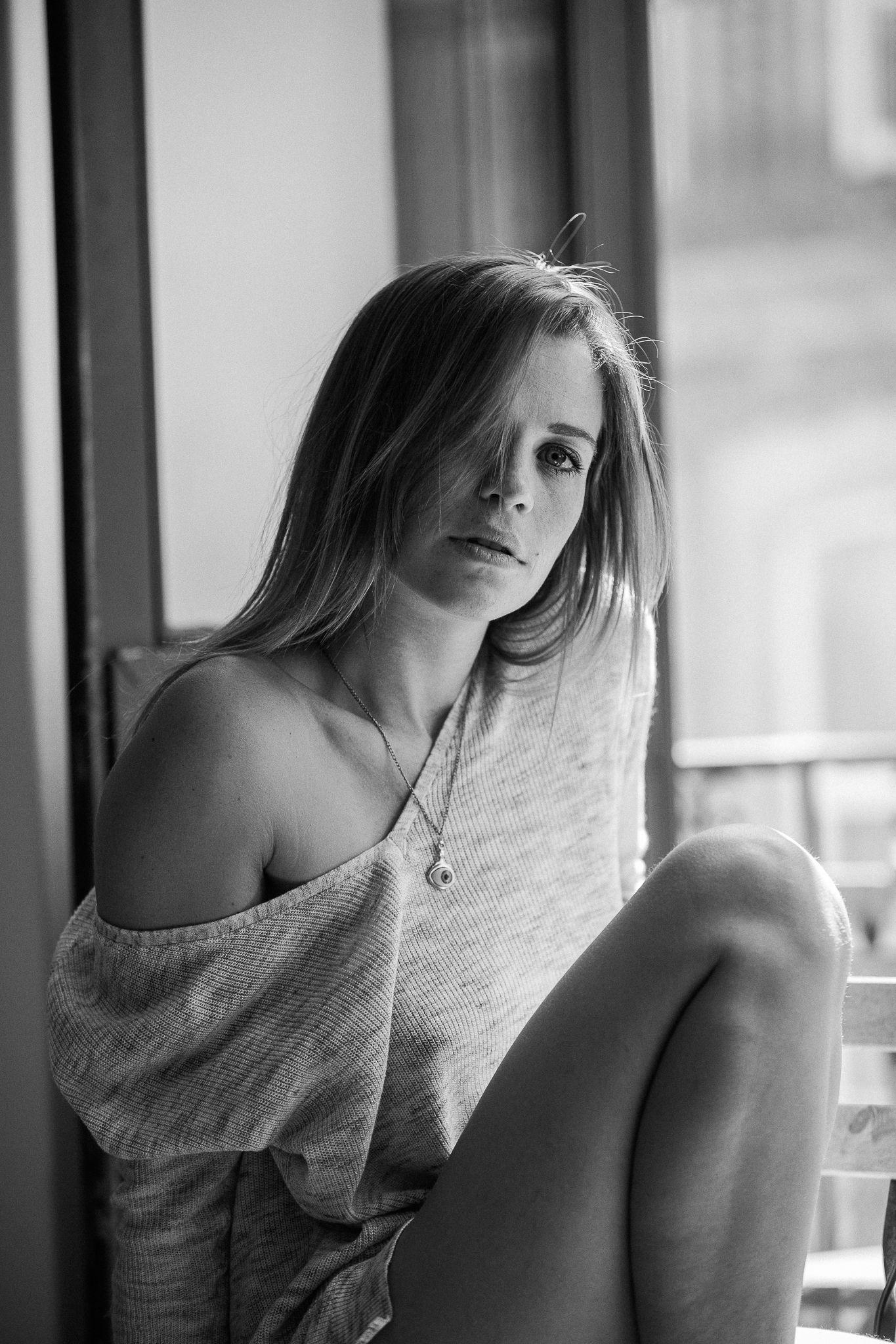 A black and white photo series showing someone in contemplative poses by a window, wearing a light-colored top.