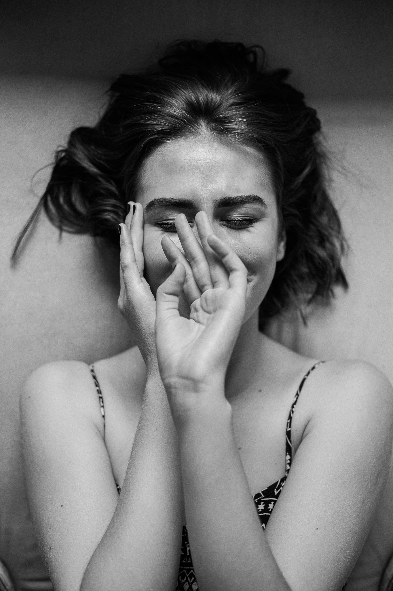 A black and white photo series showing someone covering their face with their hands in different poses.