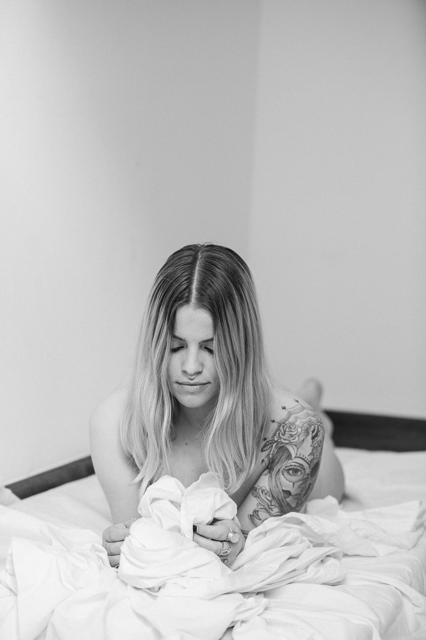 A black and white photo series showing someone lying in white bedding in four sequential poses.