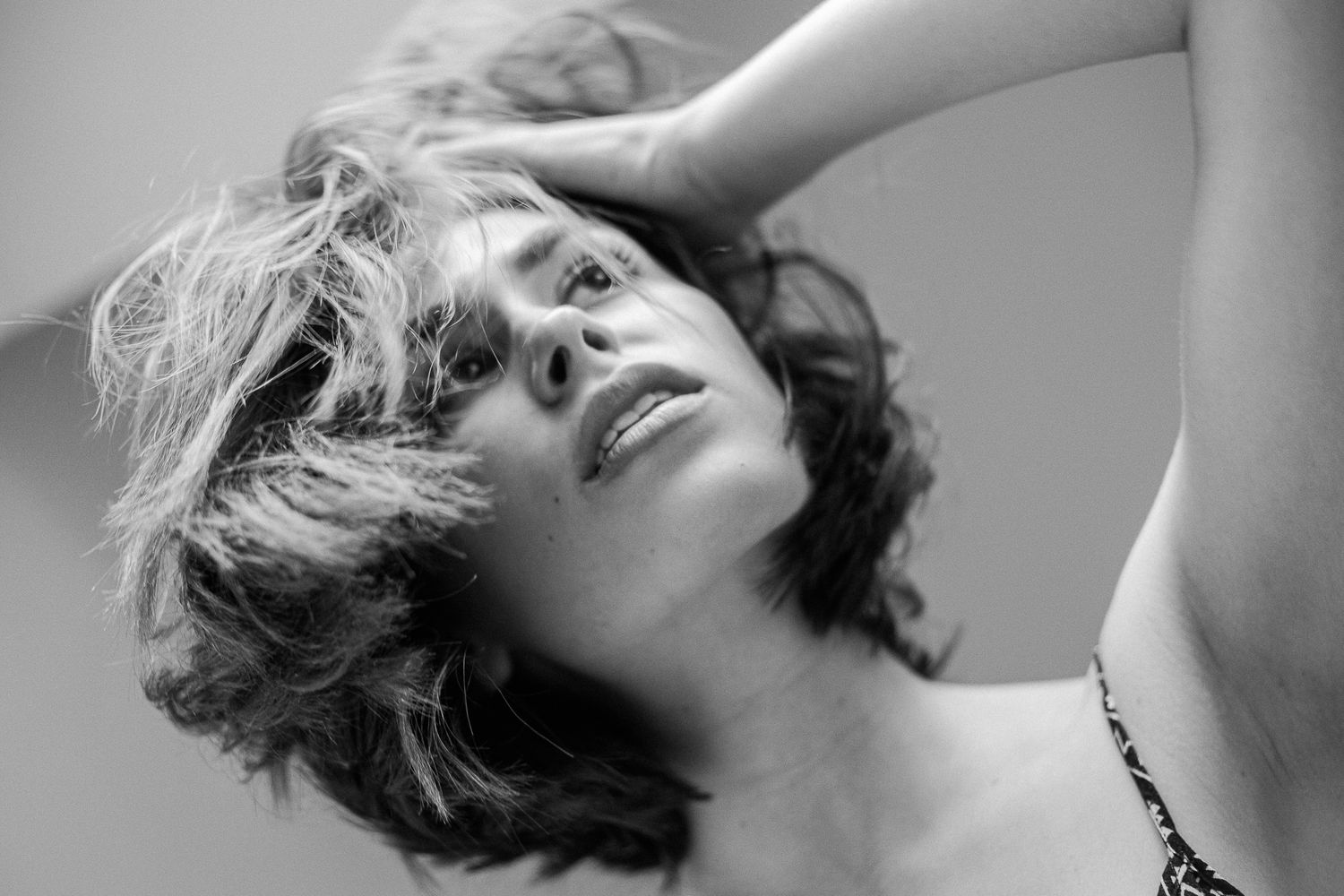 A black and white photo collage showing four different artistic portraits of a person with windswept hair.