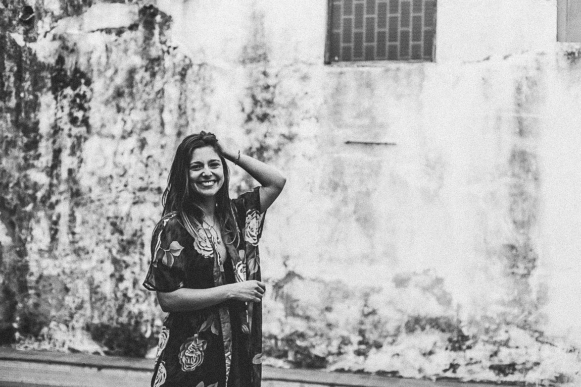 A series of black and white photos showing someone posing and laughing against a textured wall background.