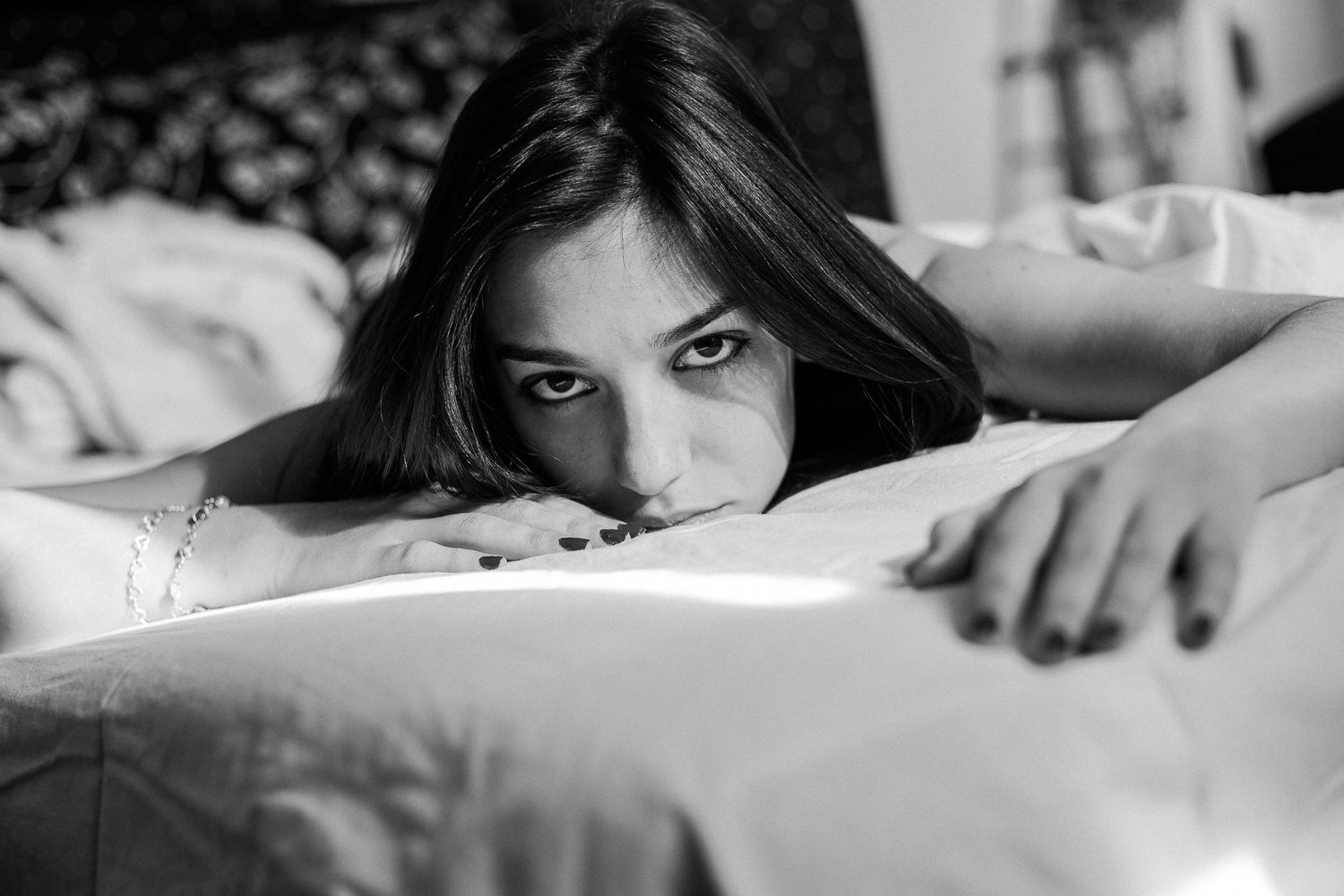 Black and white portrait series showing someone peeking out from white bedsheets in different poses and angles.