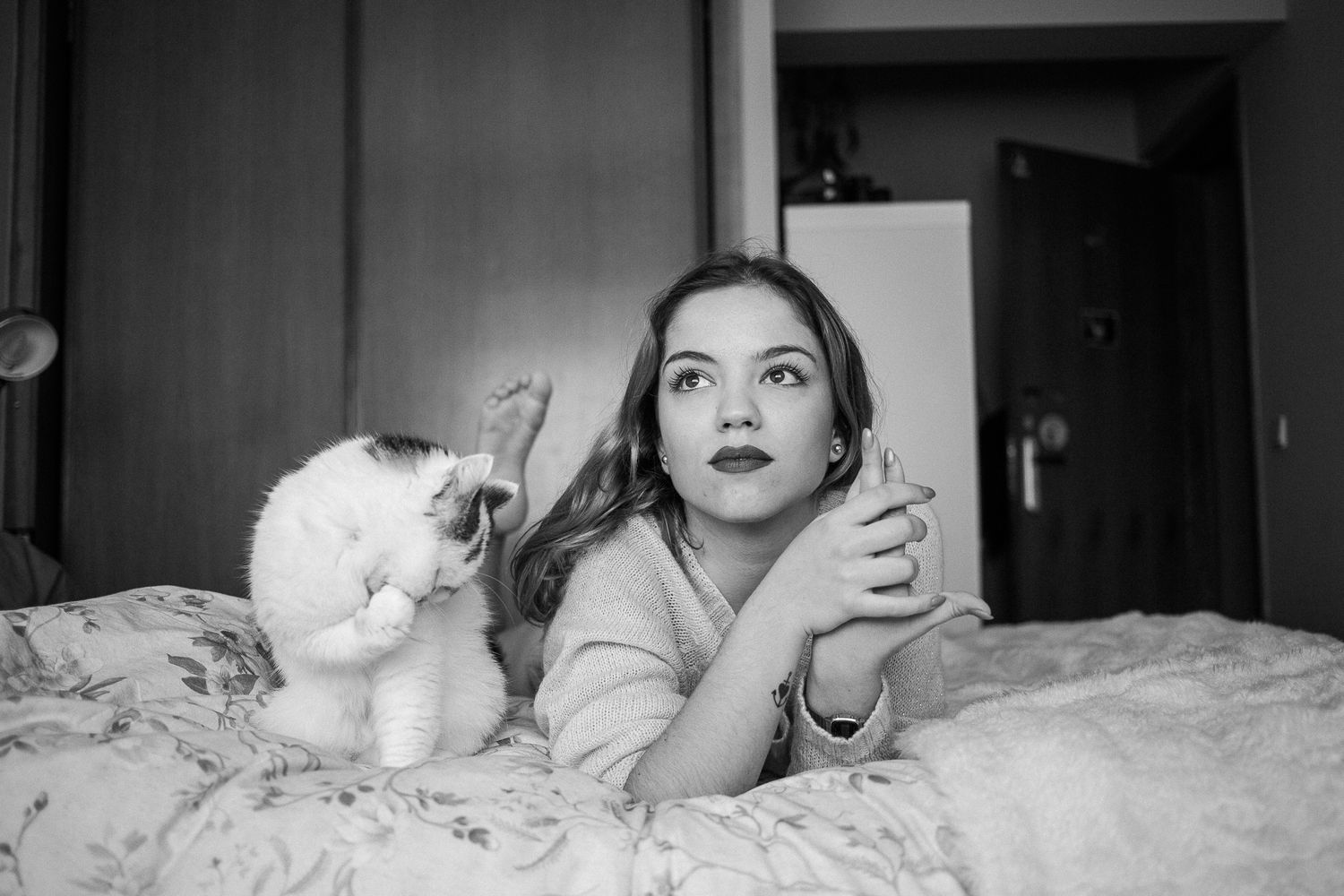 A black and white photo series showing a person relaxing in bed with a white cat in different poses.