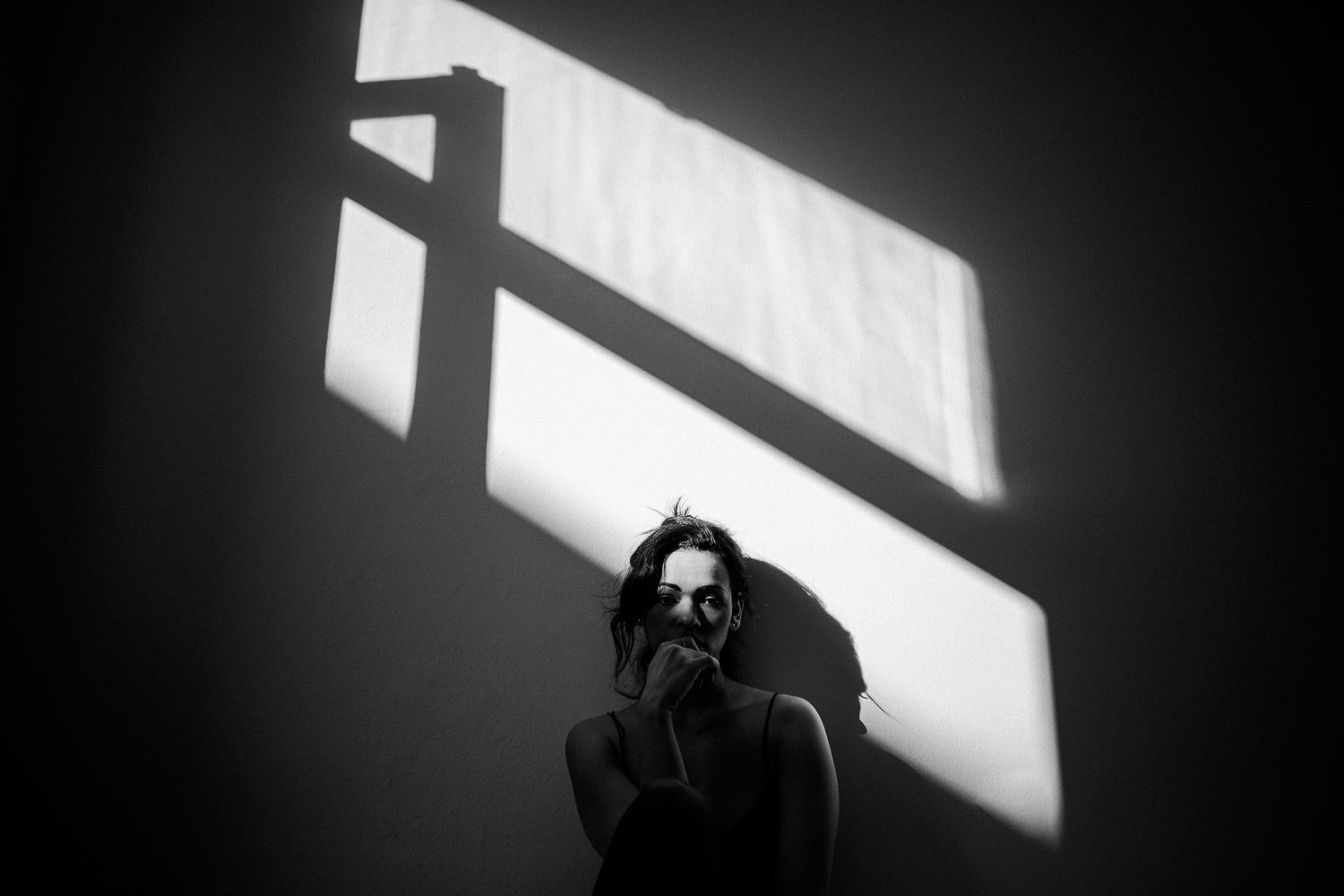 Minimalist black and white composition with strong diagonal shadows on a white wall.