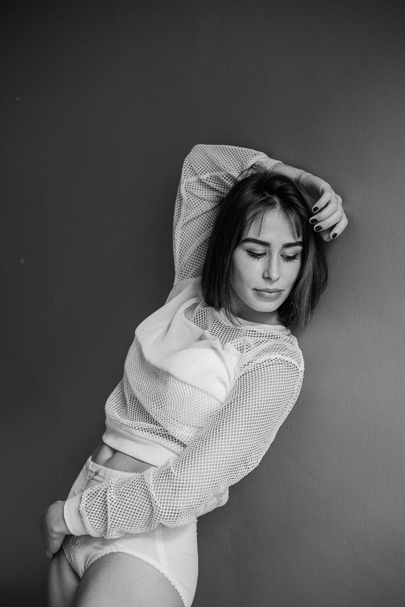 Black and white artistic portrait series showing a figure in a white sweater posing against dark background.