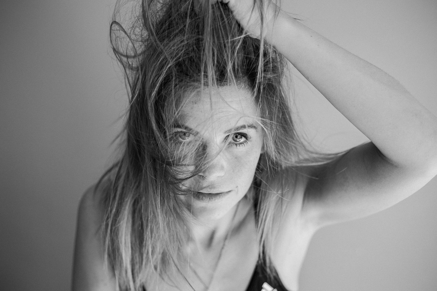 A series of black and white portraits showing a person with windswept hair in various expressive poses.