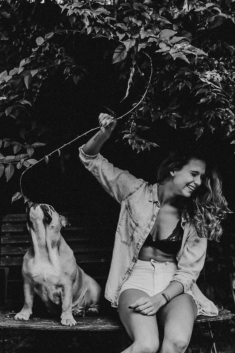 A black and white photo series shows a playful interaction between a person and a cat in a garden setting.
