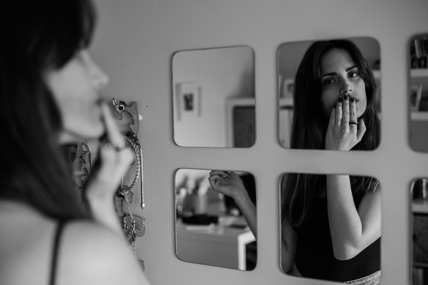 Black and white photos showing a person looking at their reflection in a bathroom mirror.