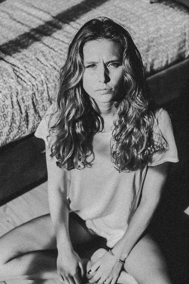 Black and white artistic portrait of a person with wavy hair in natural lighting.