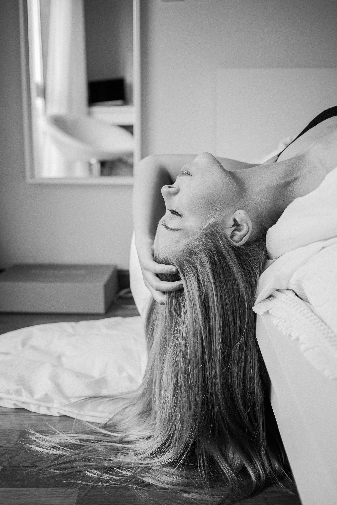 Black and white portrait series showing relaxed poses on white bedding.