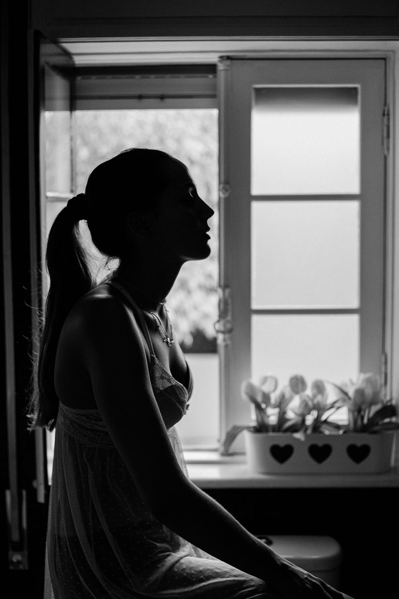 Silhouettes of people in headscarves are shown in a series of window frames creating a dramatic black and white composition.