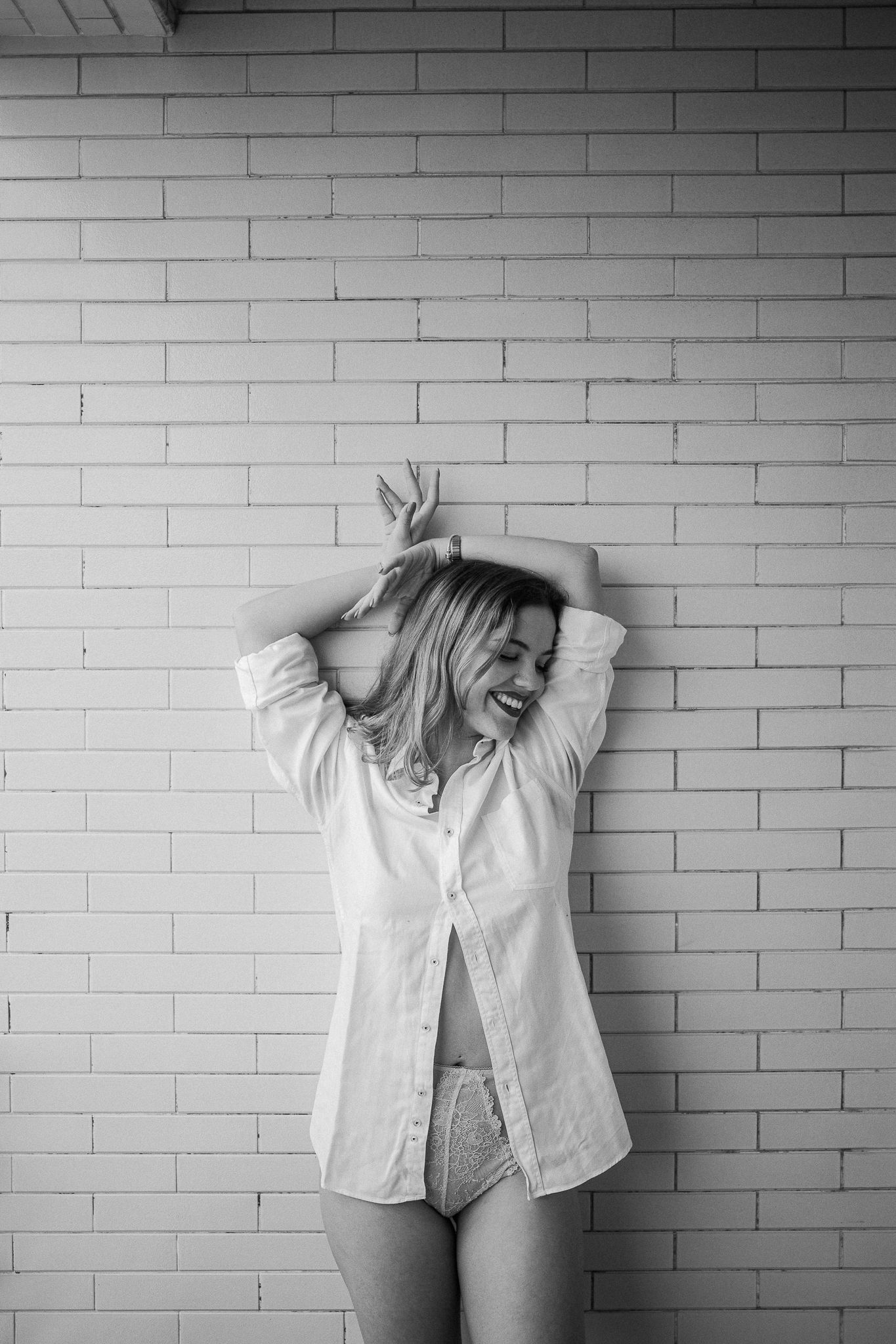 Black and white photo series showing someone in a white shirt expressing different playful poses against a brick wall.