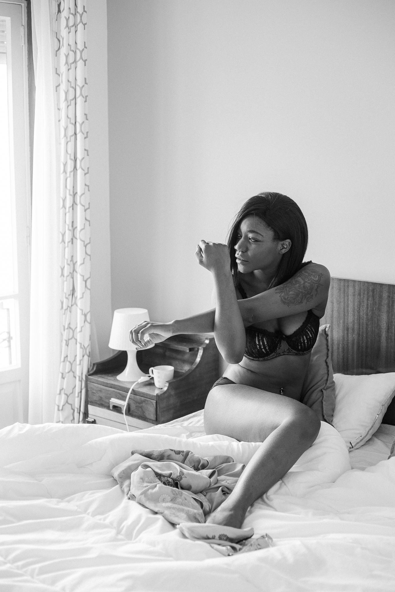 A sequence of black and white photos showing someone stretching and yawning while lying in bed with white bedding.