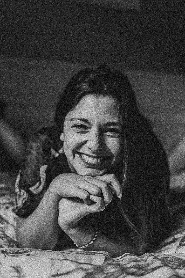 Black and white photo showing joyful laughter while lying on patterned bedding.