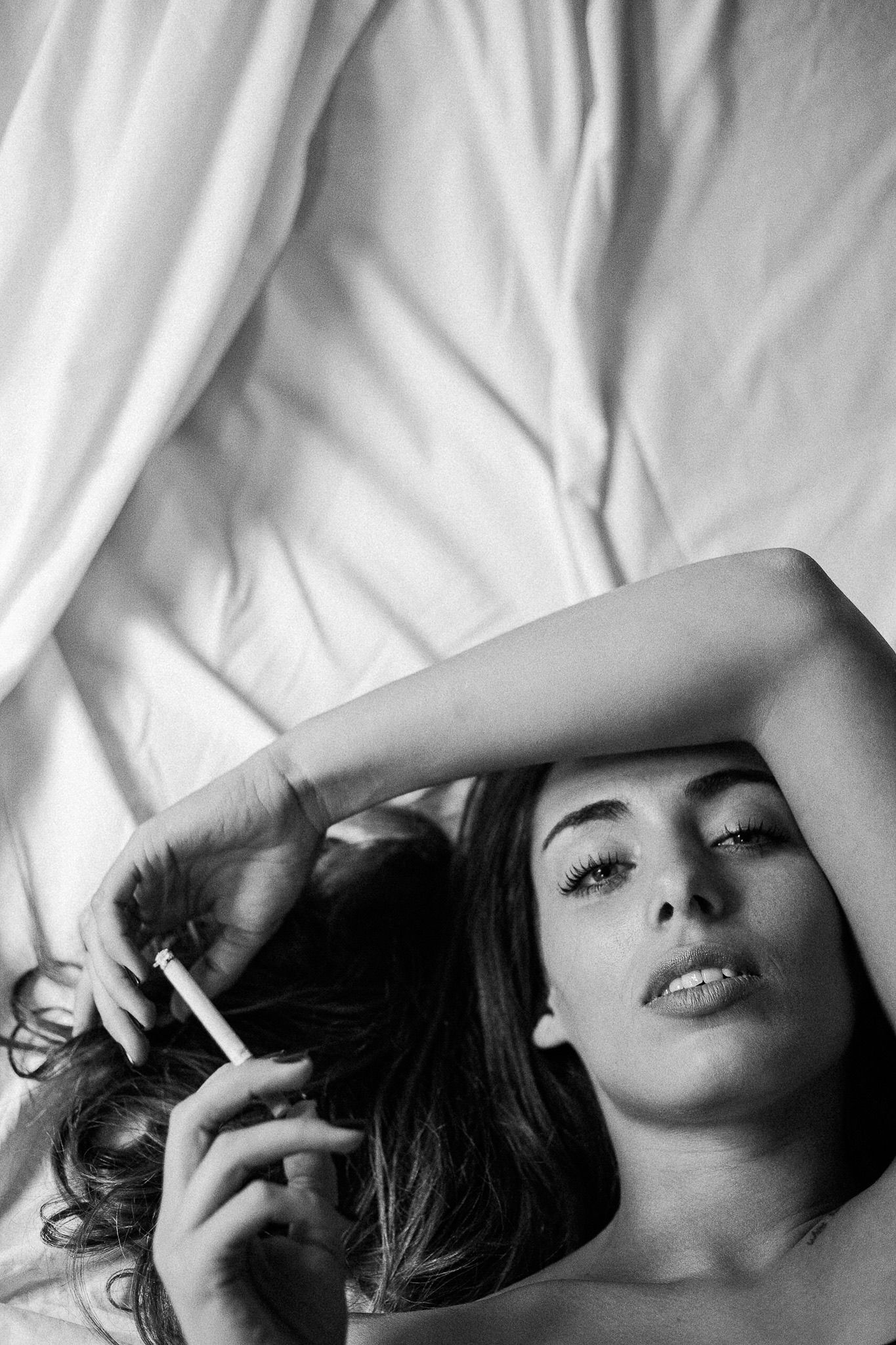 Intimate black and white bedroom portrait with dramatic lighting.