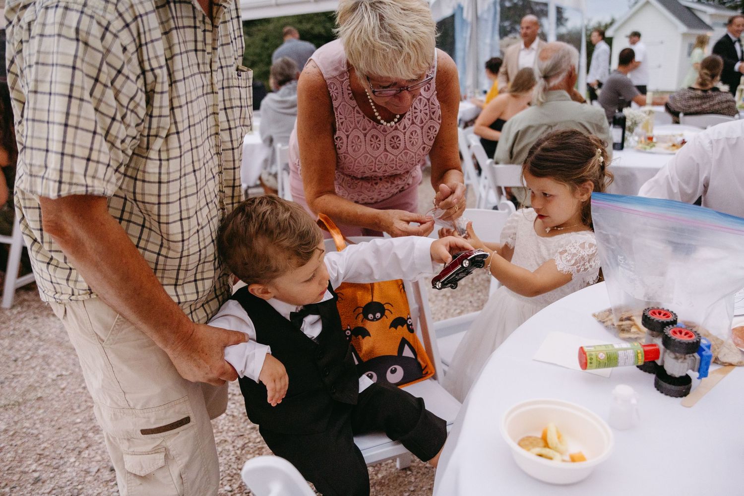 Children participate in Halloween crafts and activities at an outdoor event with family members helping at tables.