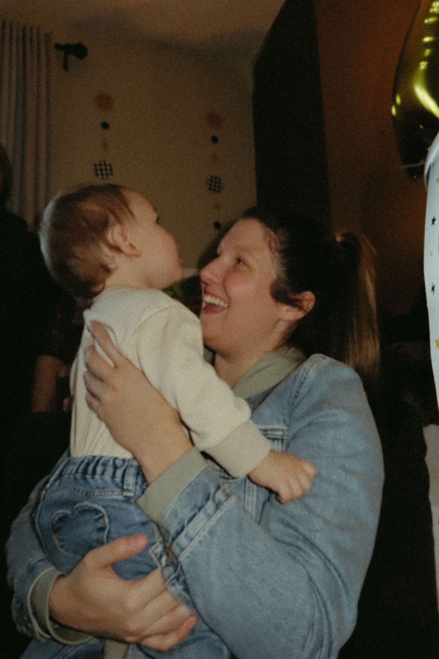 A tender moment of joy and laughter shared between a parent and small child in denim clothing.