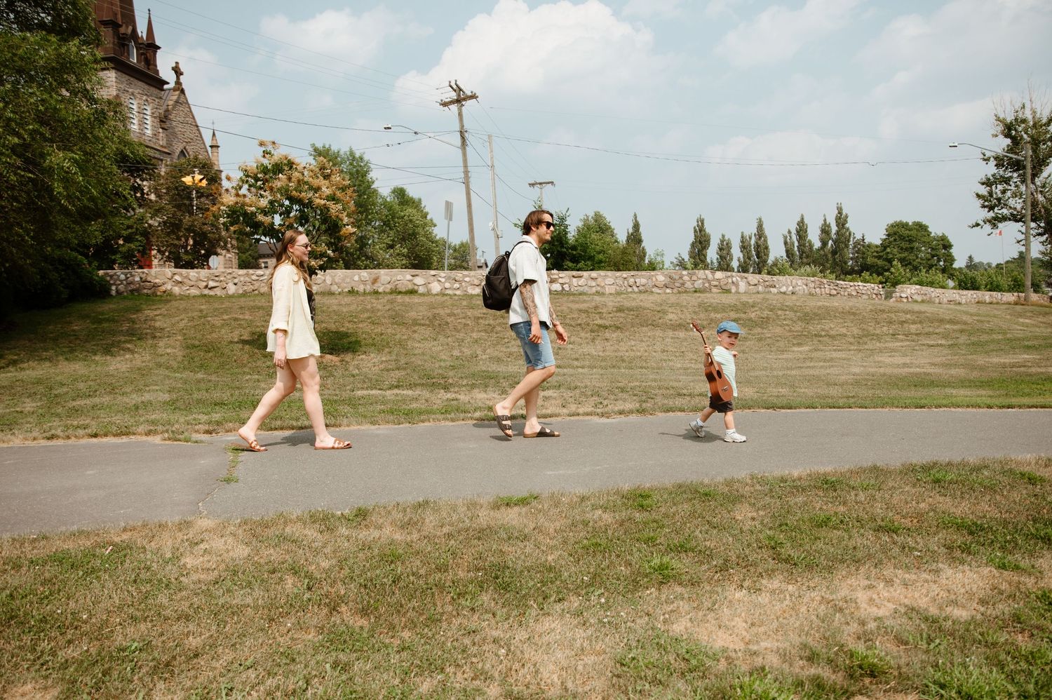 People walking along a grassy hillside path on a sunny summer day.