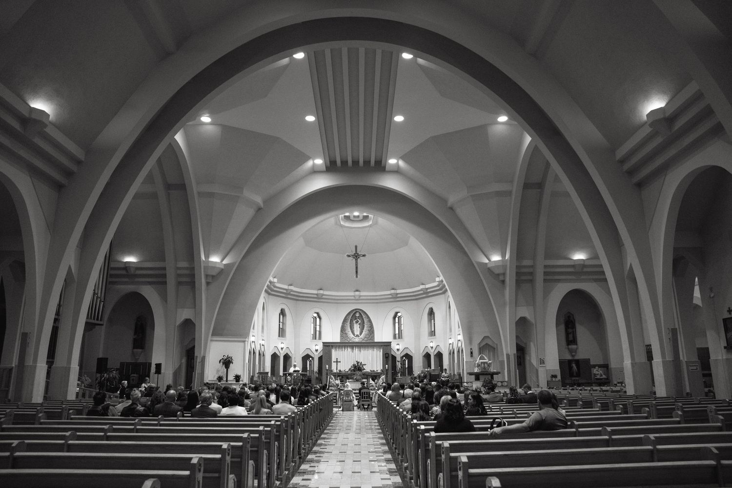 Interior panorama of a church sanctuary with arched ceilings and rows of wooden pews.