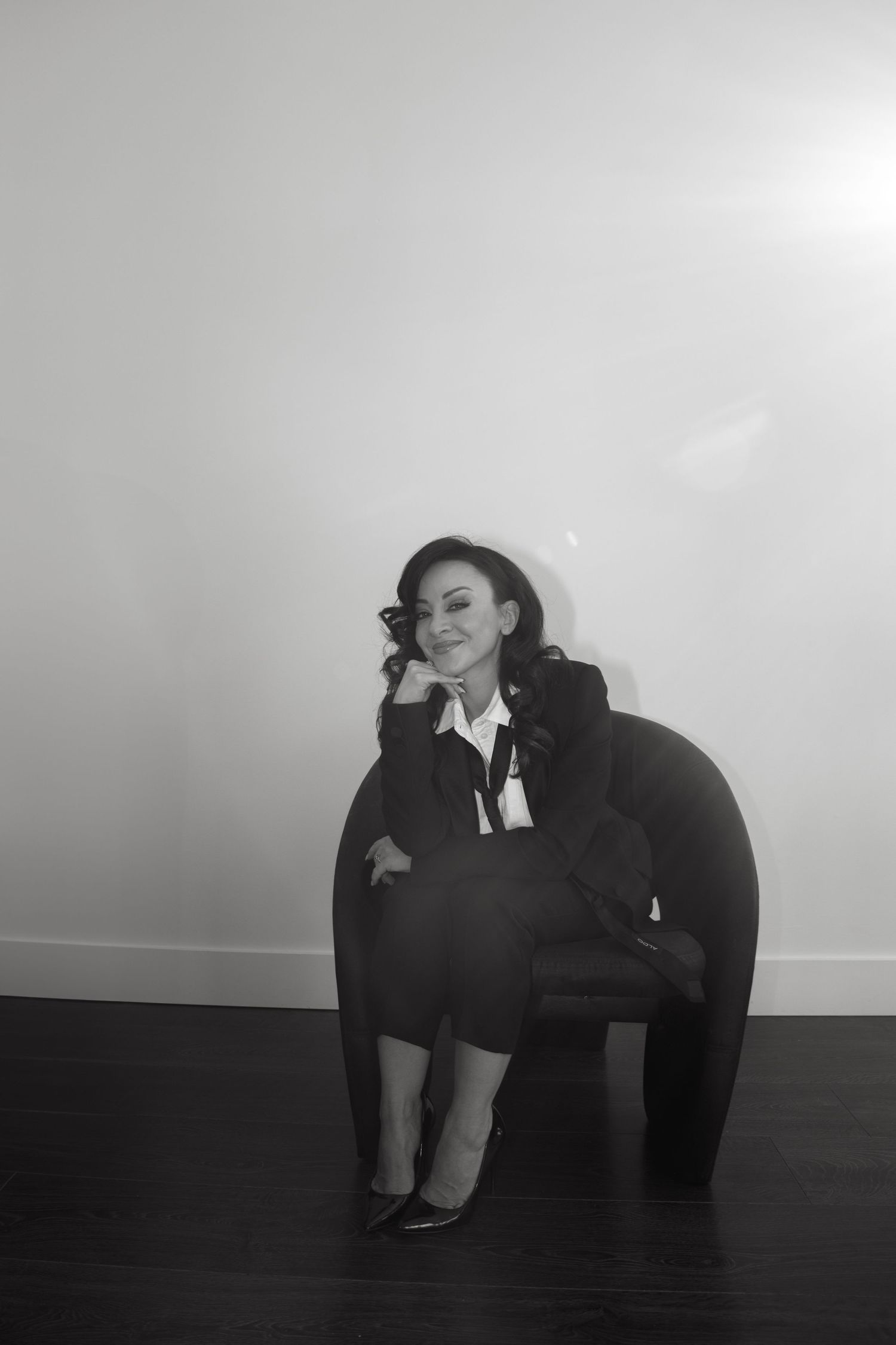 A series of black and white photos showing a person in dark clothing curled up against a white wall in different positions.