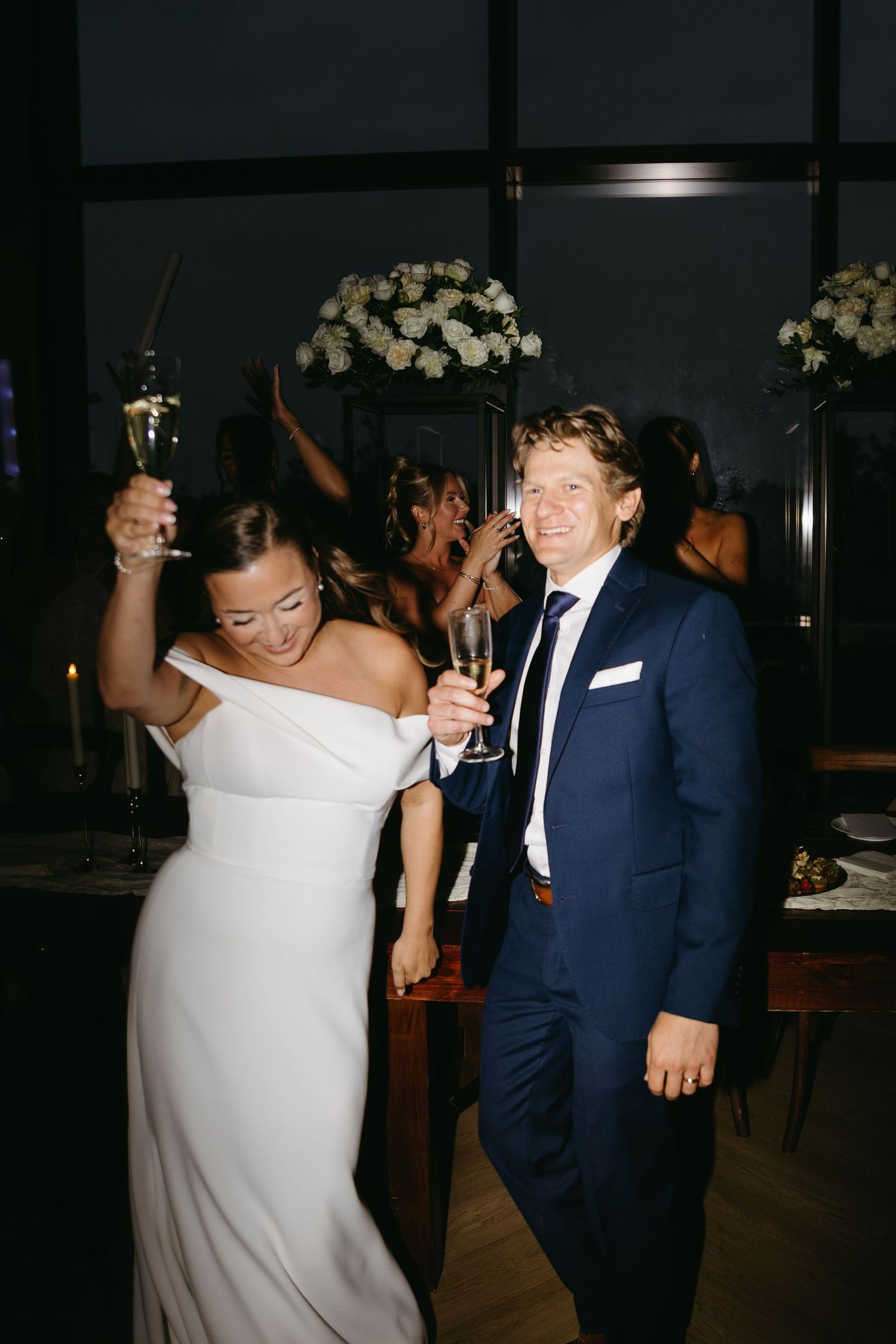 A couple in formal wedding attire share a dance together at an evening reception.