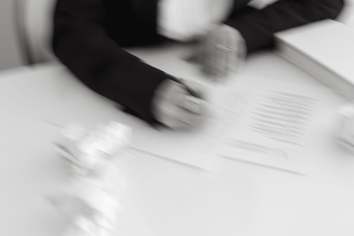Blurred motion shot of hands signing documents on white table.