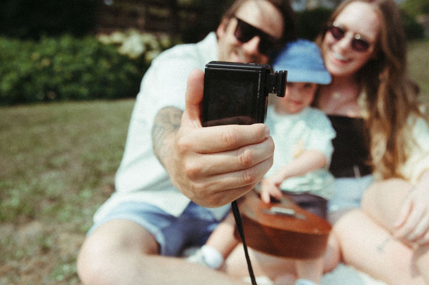 A couple takes a selfie together outdoors on a sunny summer day.