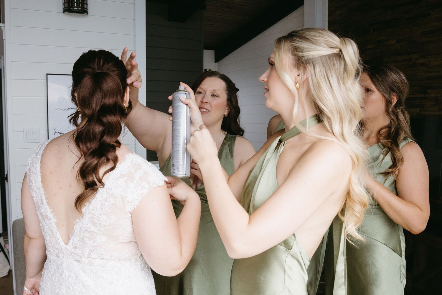 A group of bridesmaids in sage green and white dresses dance and celebrate at a wedding reception.