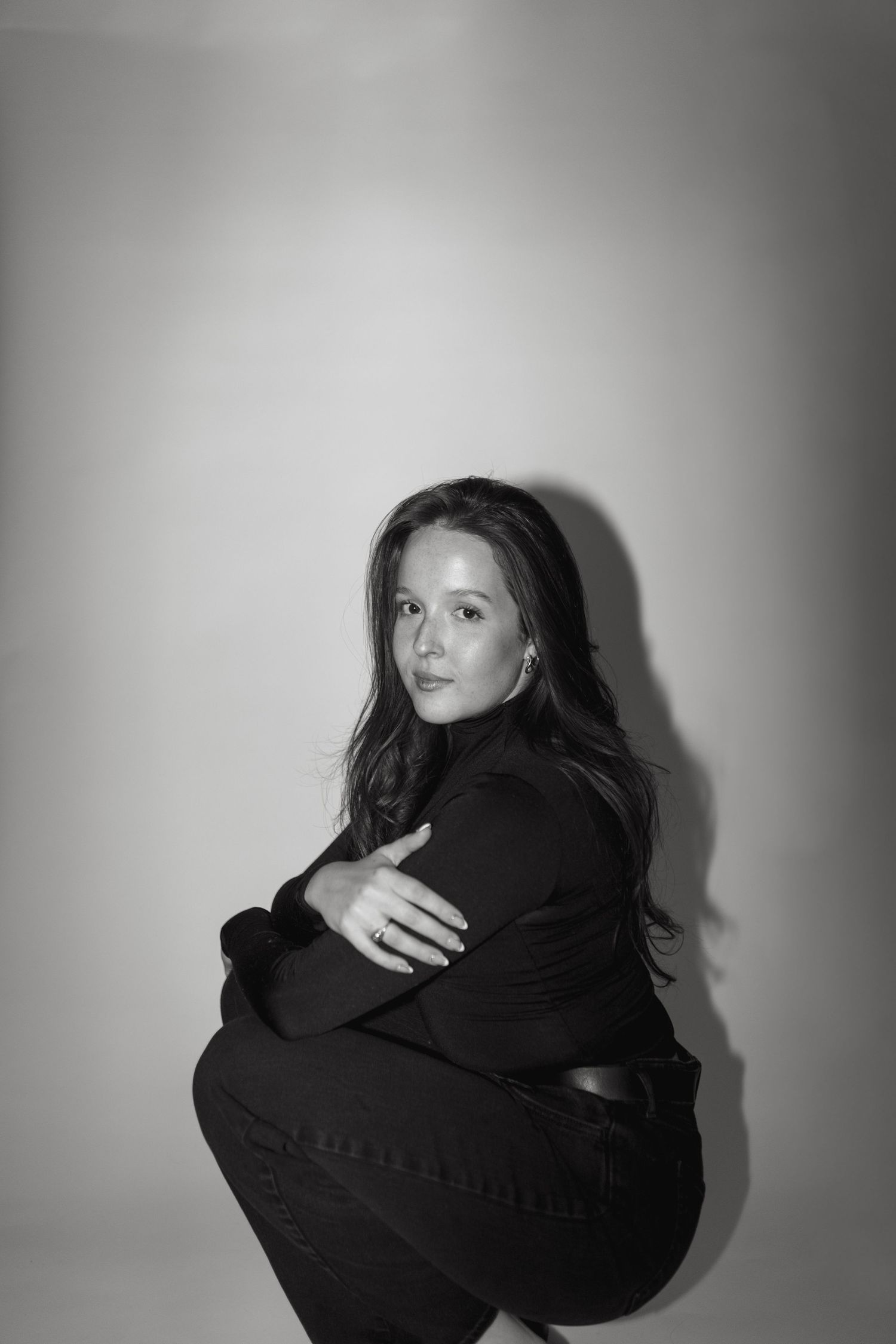 Black and white portrait series showing a figure in dark clothing against a light background creating dramatic contrast.