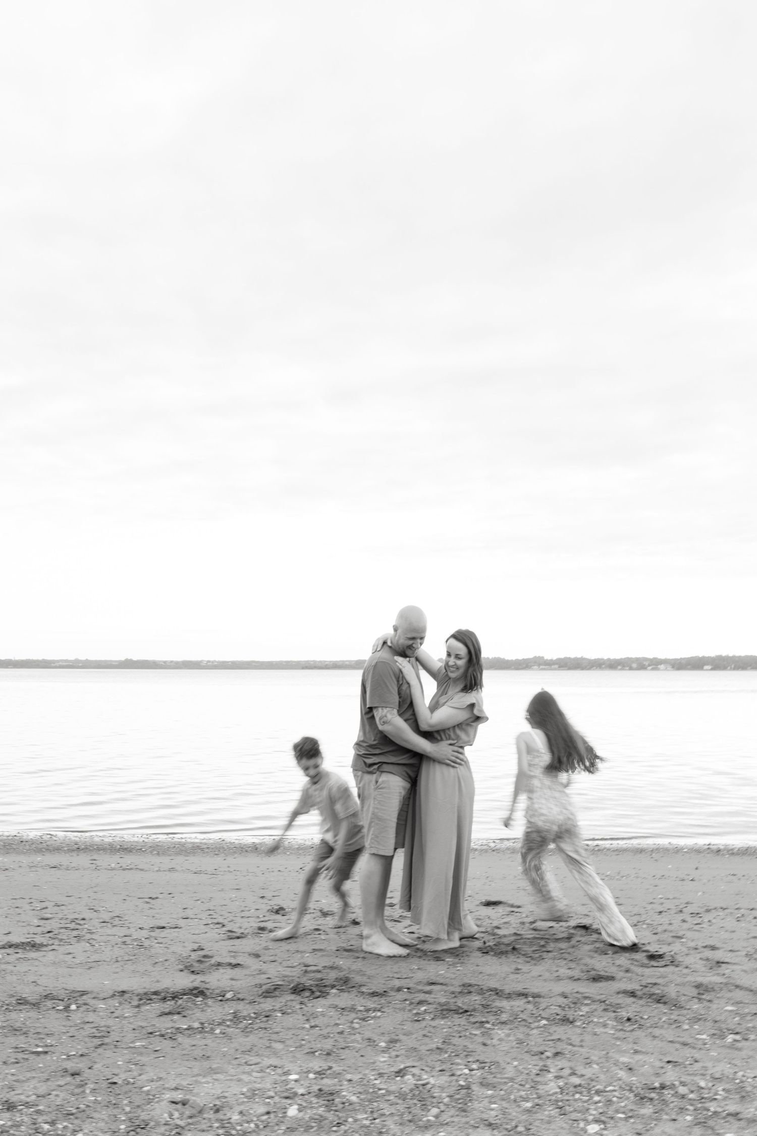 A sequence of black and white photos showing people playing and falling on a beach near the ocean.